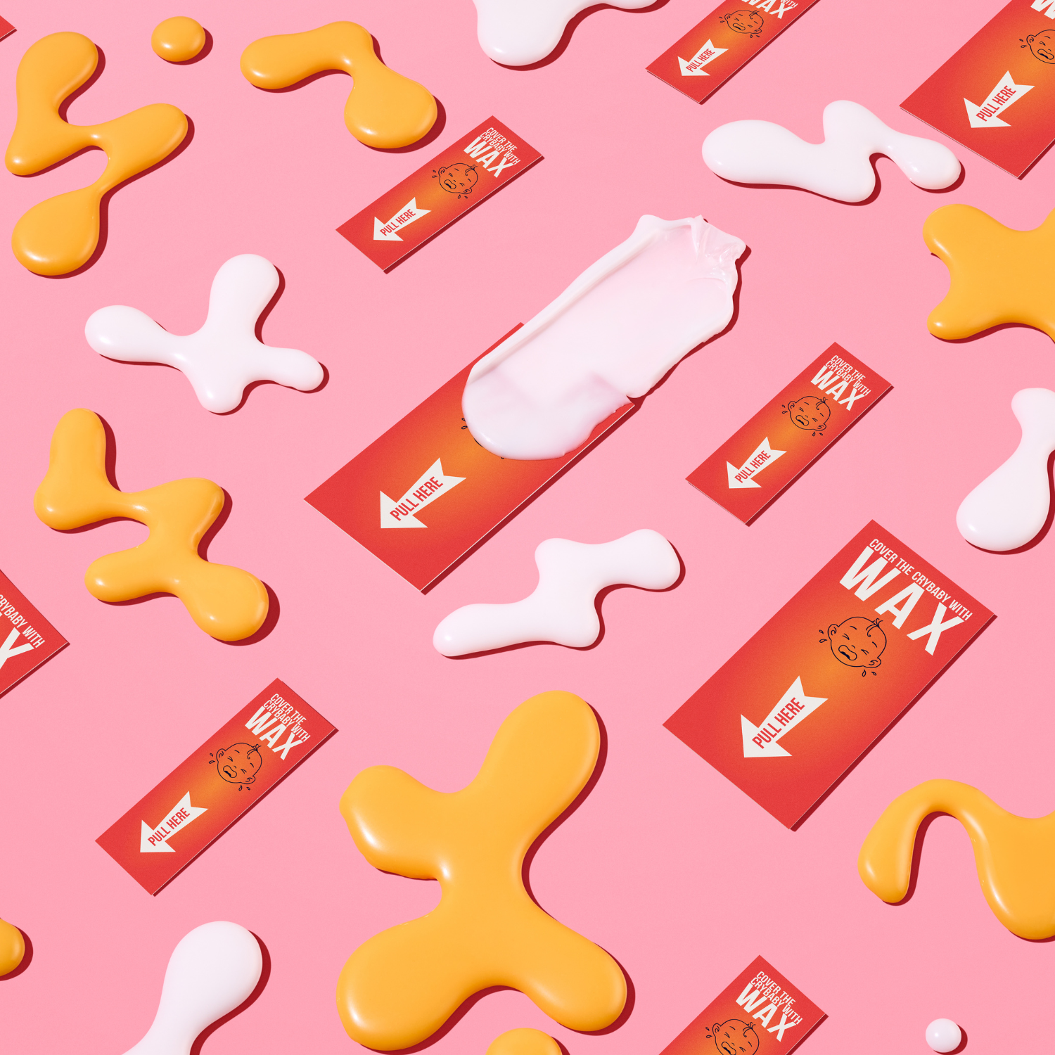Cream and amber rosin-free hard wax beads with Crybaby Wax pull-tab strips on a pink background