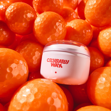 Crybaby Wax Mini Meltdown Machine warmer resting in a bed of golf balls, a golf-ball-size compact warmer