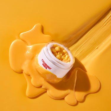 Crybaby Wax jar tipped over with amber hard wax beads spilling out for at-home hard waxing