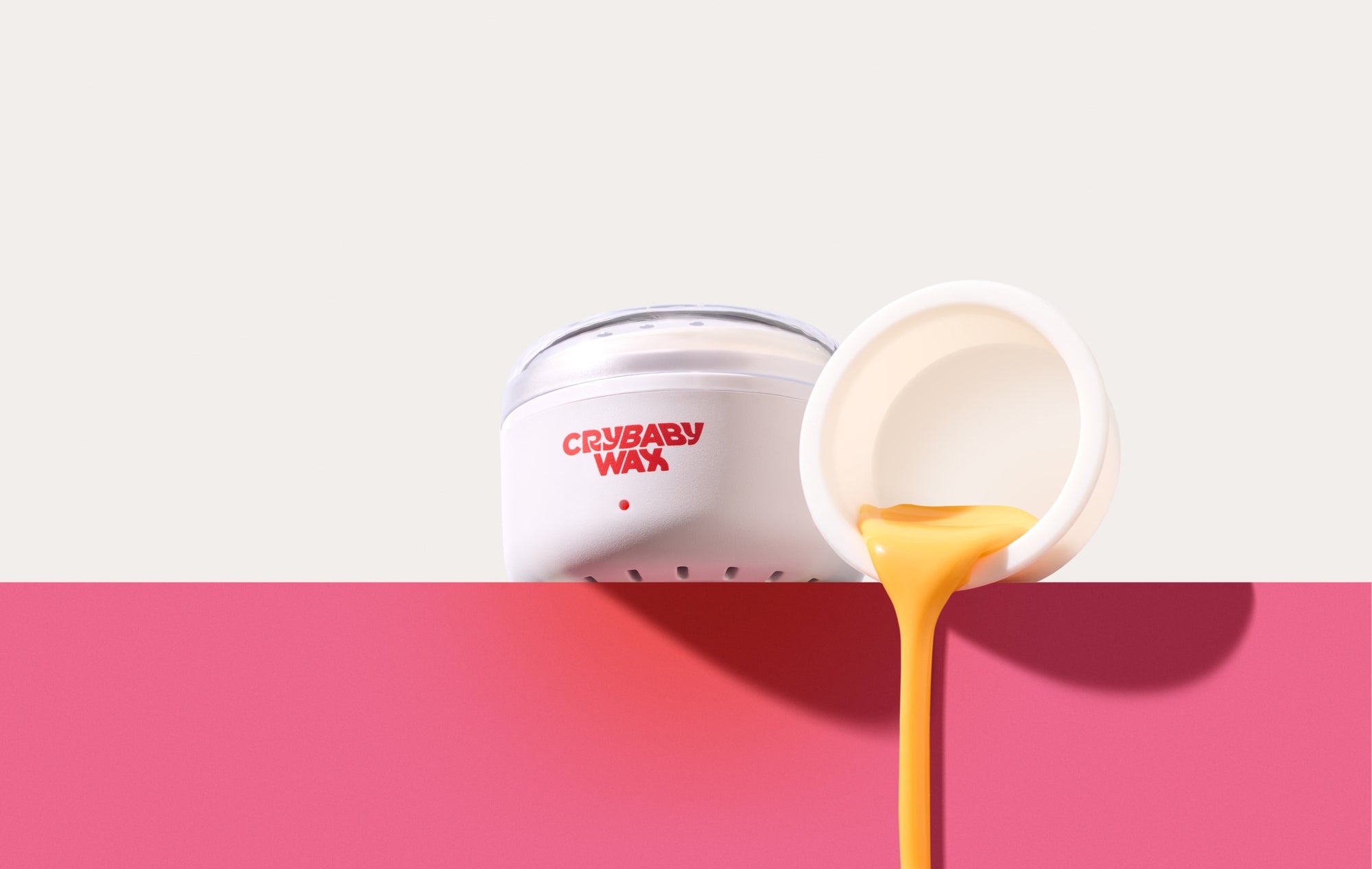 The Mini Meltdown Machine wax warmer beside a jar pouring melted Crybaby Wax hard wax over a pink ledge