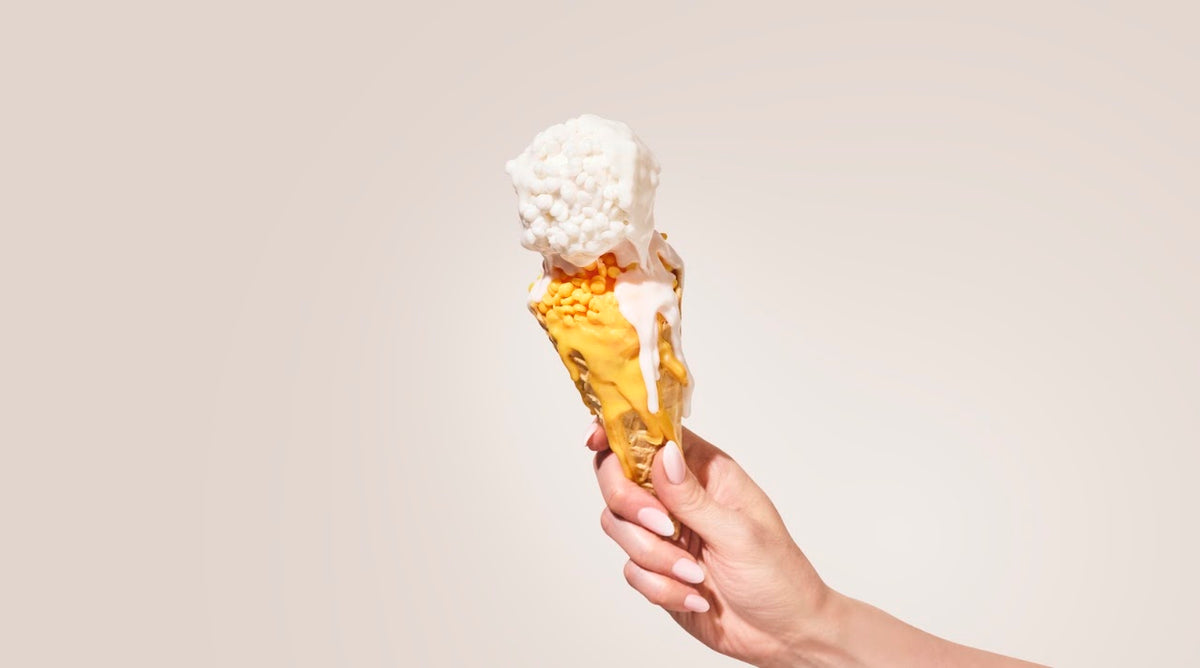Hand holding a wax bead ice cream cone with melted wax drips